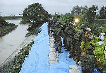 Japan Ground Self-Defense Force soldiers place sandbags to reinforce embankments on Shonai River as Typhoon Roke strikes Nagoya, central Japan. [Japan Ground Self-Defense Force]